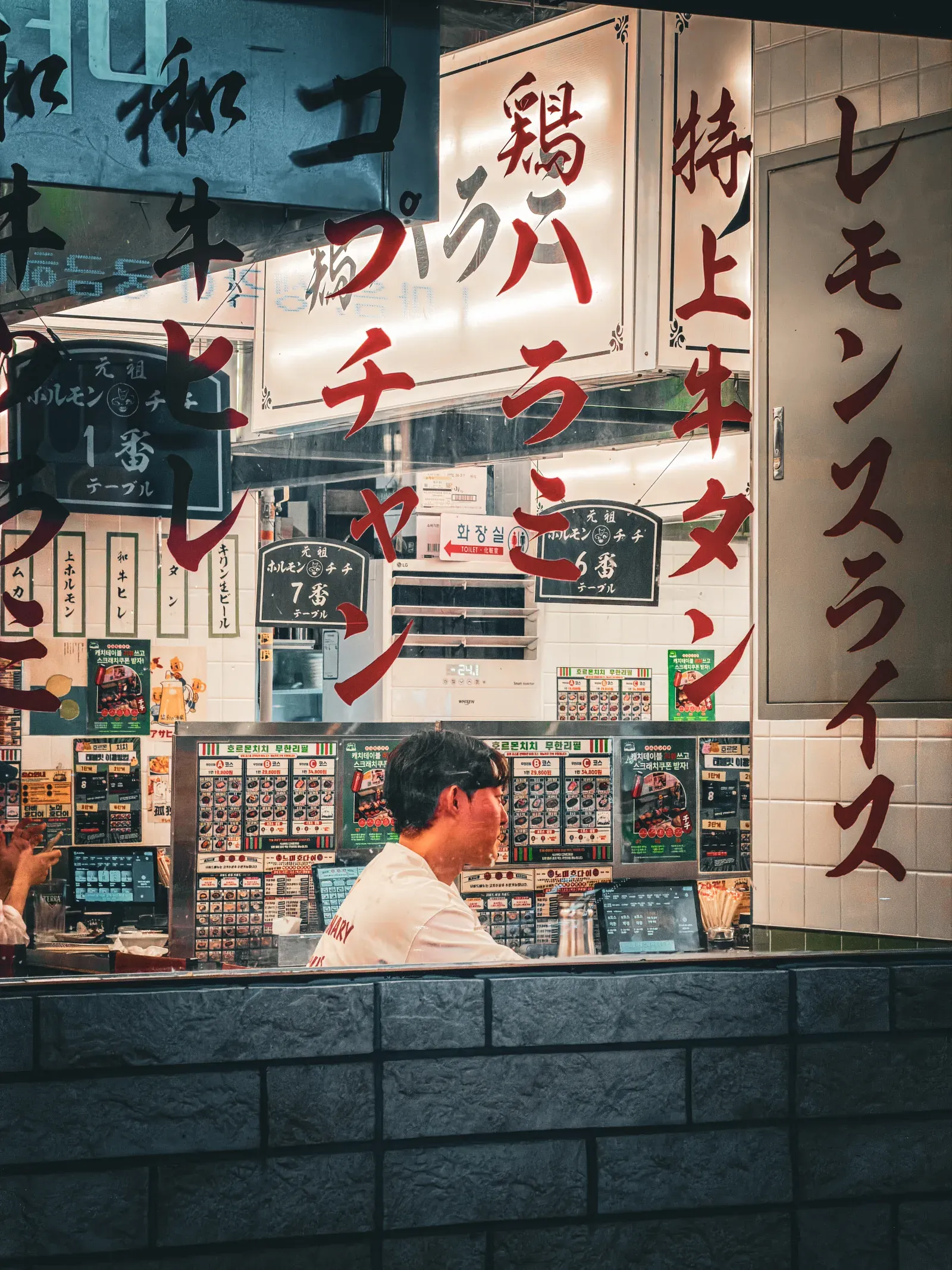 A street food stall in Busan: the cook behind the counter, dense signage