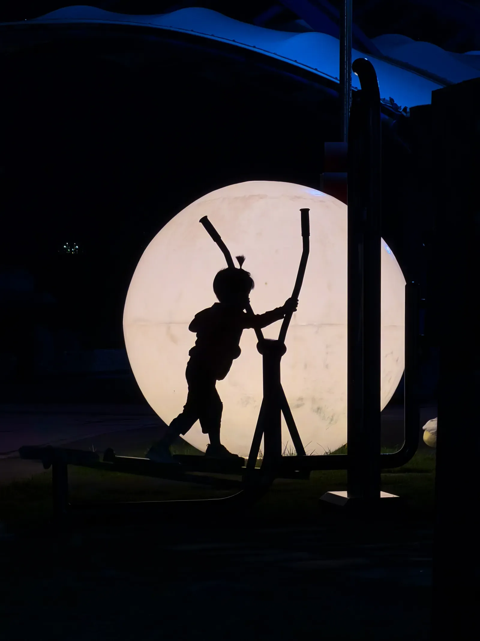 Two figures silhouetted inside a lit circle at night