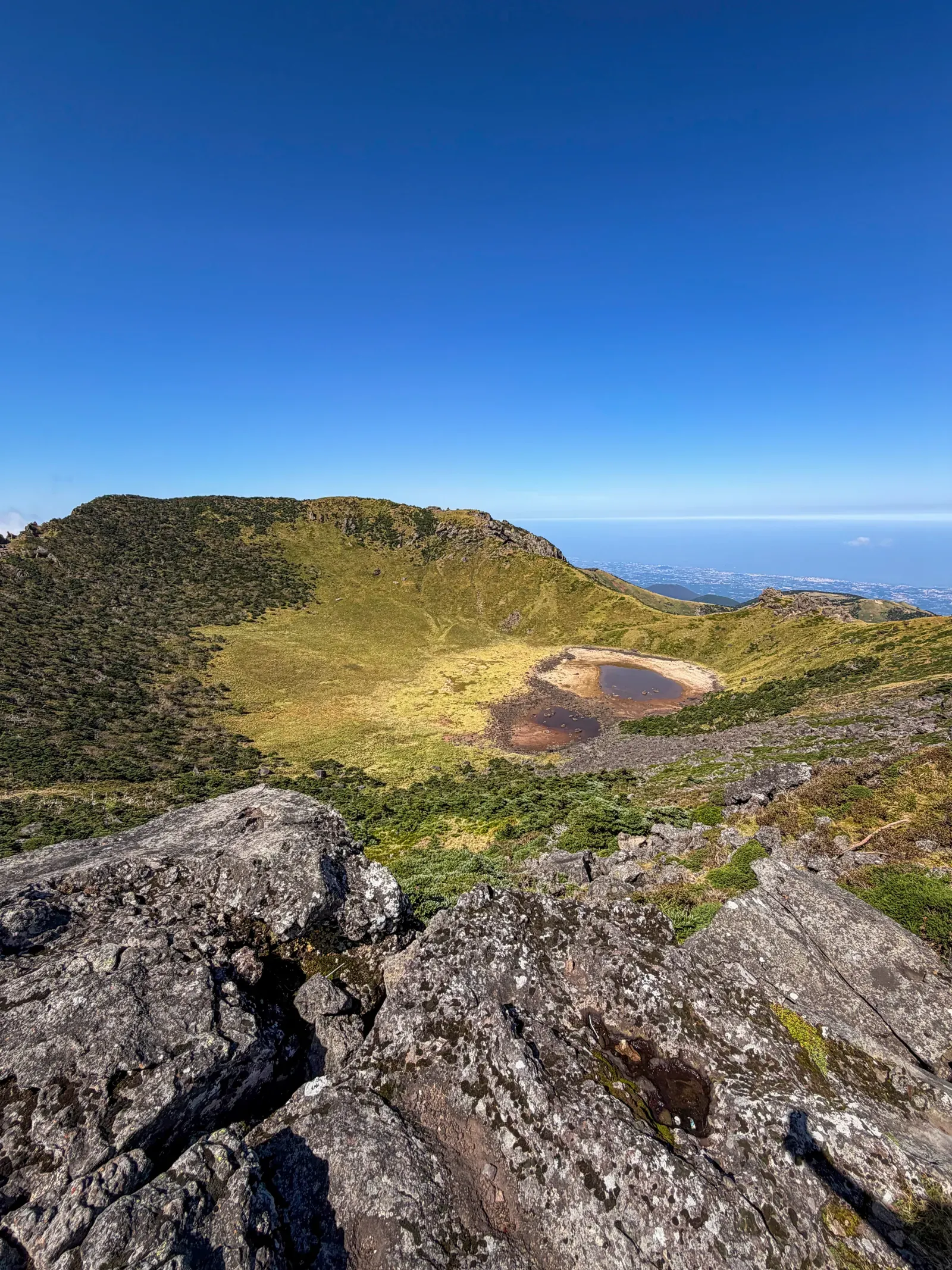 The rim of a volcanic crater on Jeju, the sea beyond