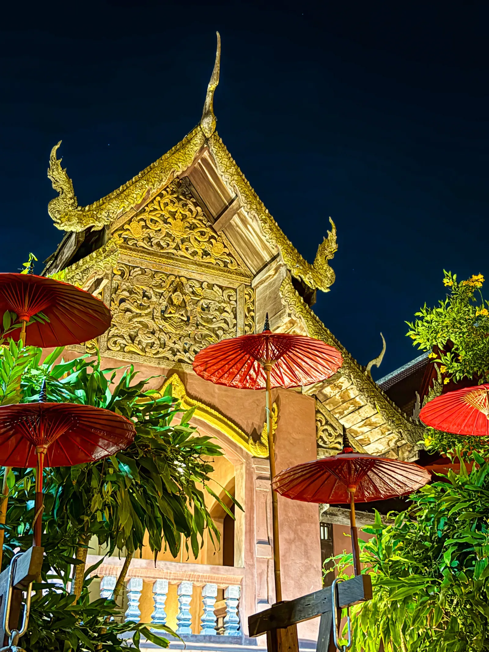 A temple roof and red parasols lit at night in Chiang Mai